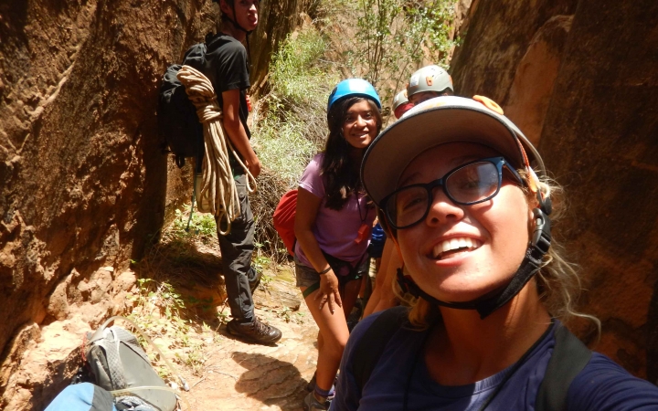 A small group of people smile for a photo between two canyon walls.